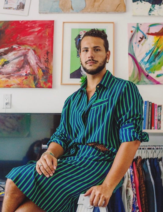 Samy Nemir Olivares in a striped shirtdress with paintings behind him